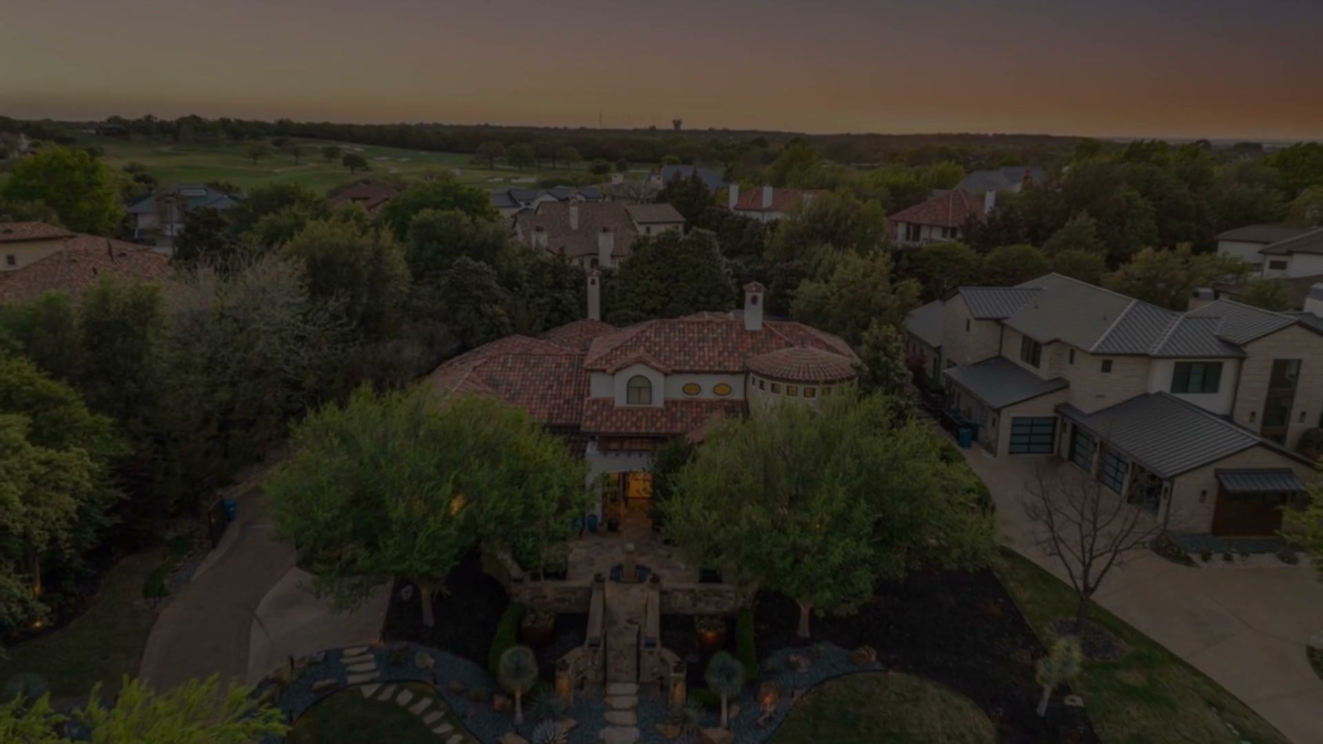Aerial view of the estate at dusk inside the Vaquero Club, the tile roof at the center of the neighborhood