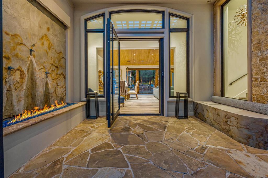 Entry hall with a stone-slab fire-ribbon fireplace and flagstone floor, doors open through to the backyard