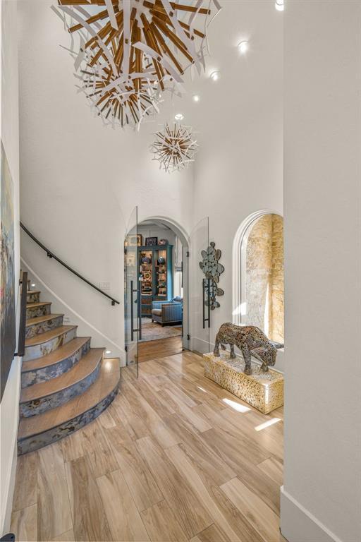 Entry foyer with a curved spiral staircase, marbled stone risers and twin starburst chandeliers