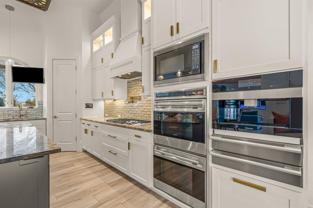 The chef's kitchen appliance wall: dual Wolf ovens, a Miele built-in coffee system, subway tile