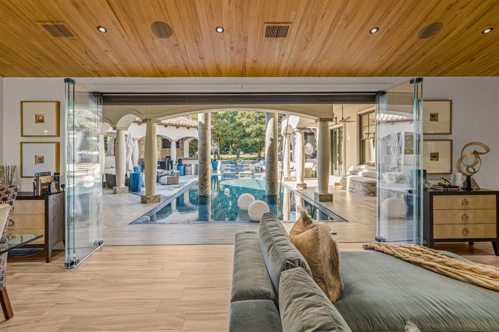 Family room with sliding glass doors folded fully open to the columned pool loggia