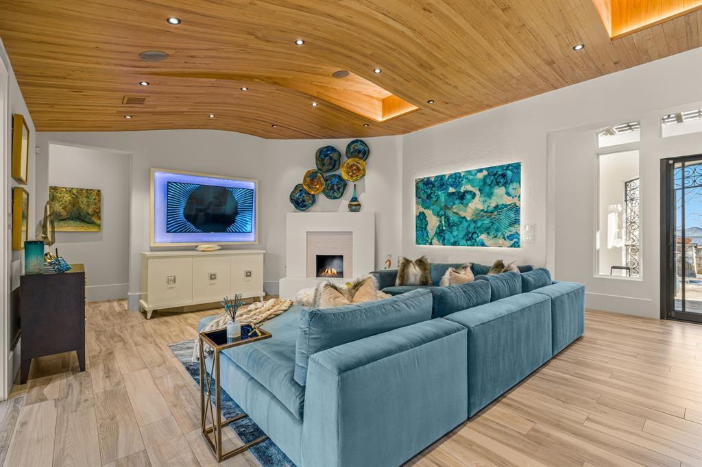 Family sitting area with a teal sectional and lit fireplace under the sculptural wood ceiling