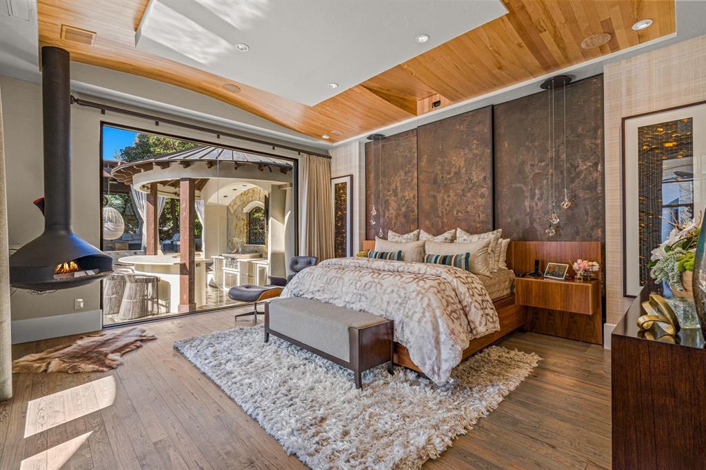 The primary suite with a suspended cone gas fireplace and floor-to-ceiling glass to the backyard