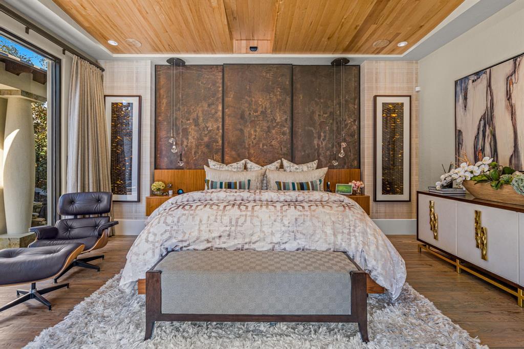 Primary suite from the foot of the bed with bronze headboard and a leather lounge chair