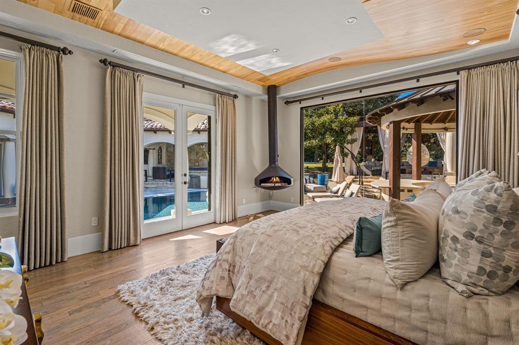 Primary suite toward the pool with a suspended cone gas fireplace and glass doors to the cabana