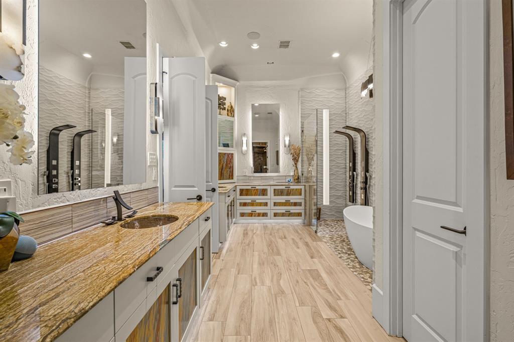 Primary bath with dual vanities, wave-textured tile and a freestanding soaking tub