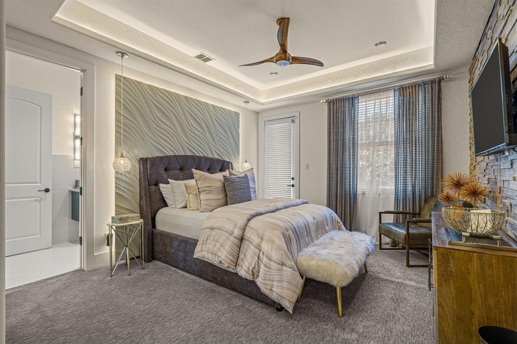 Secondary suite with a gray tufted headboard and a stacked-stone television wall