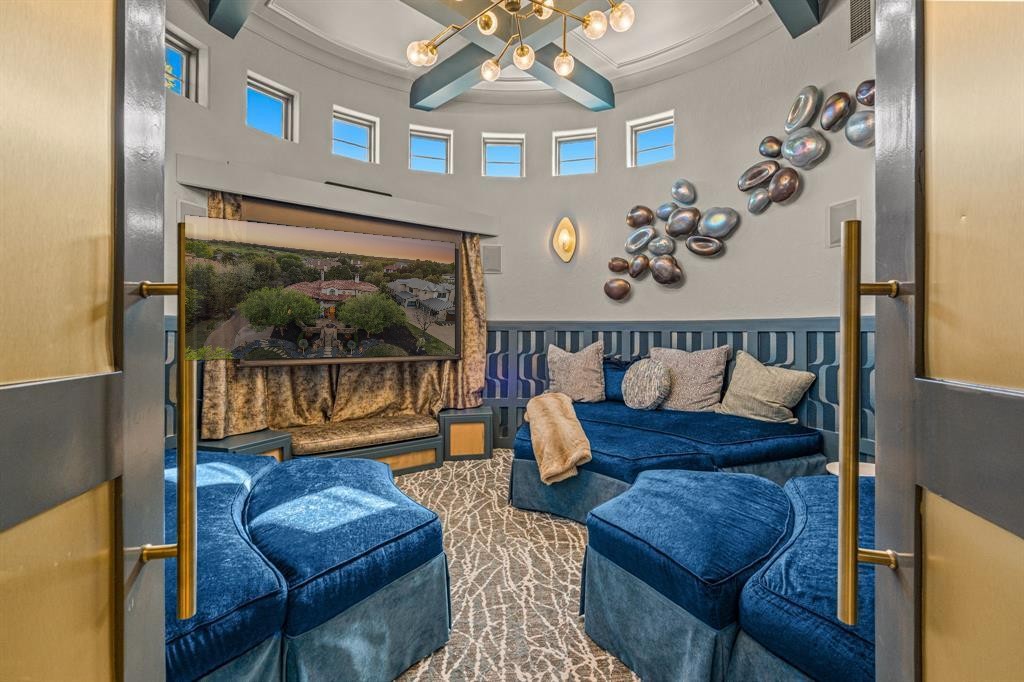 The circular media room: a genuinely round space with a domed ceiling, curved band of windows, custom curved blue-velvet seating, and the aerial view of the estate on the projection screen