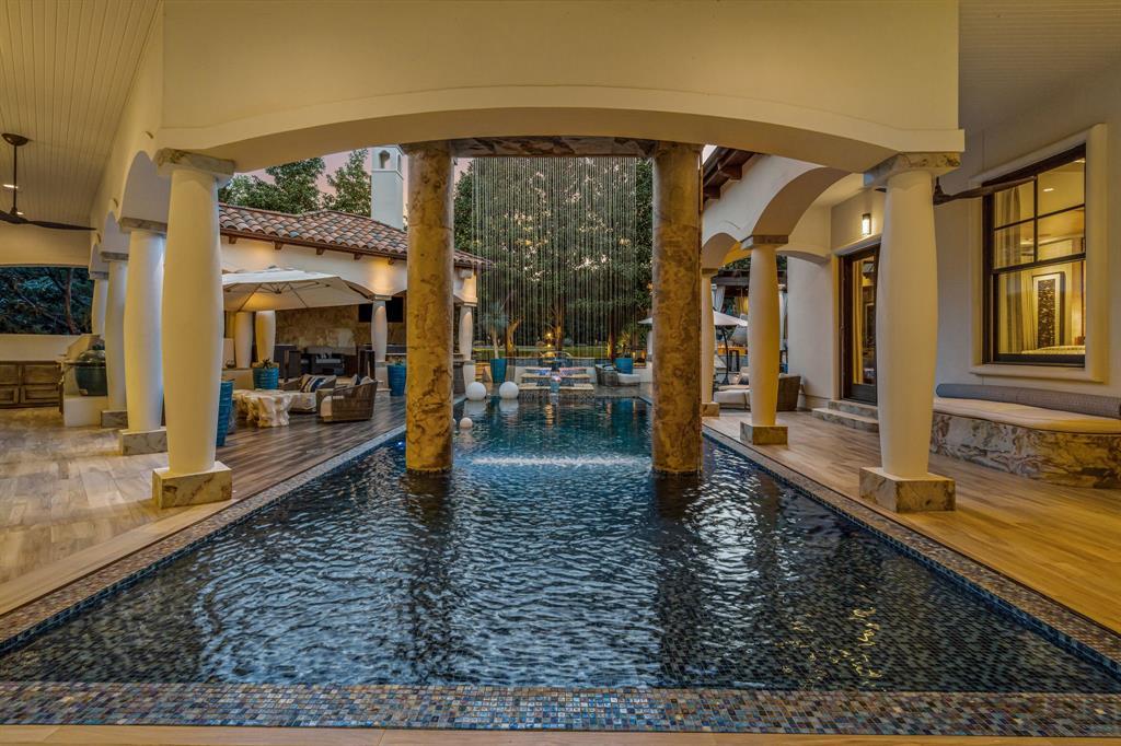 Covered pool loggia with stone columns, the pool running under the pavilion and a rain-curtain water feature