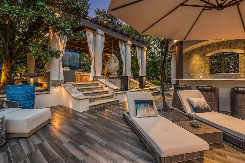 Backyard lounge with a draped pergola, a hanging egg chair and chaise lounges