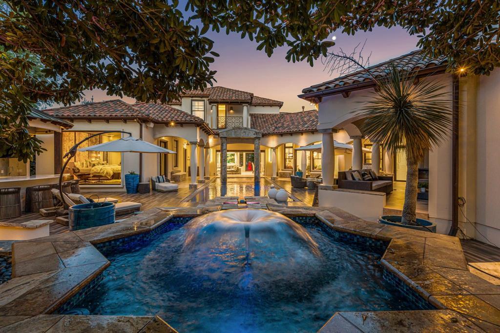 The backyard resort at dusk, the house glowing behind a chilled pool and spa